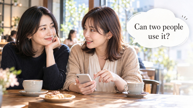 Two women talking over a phone at a café table