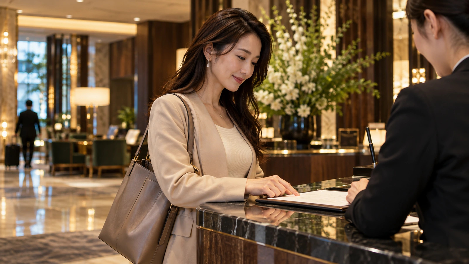 A woman examines a folder or documents with reception staff at an elegant marble hotel reception with large floral arrangements; a tablet or electronic folder is visible at the counter.